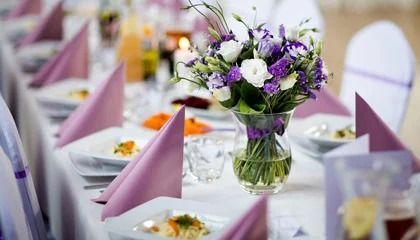 Elegant banquet table with purple folded napkins and a vase of purple and white flowers
