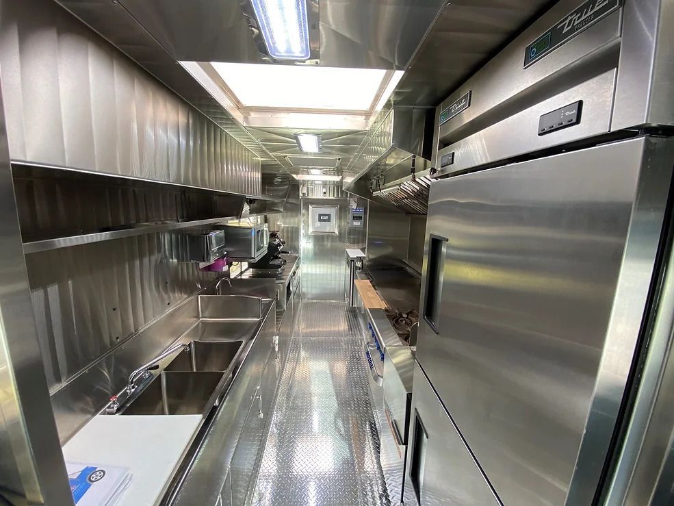 Narrow stainless steel commercial kitchen aisle with appliances and prep counters on both sides