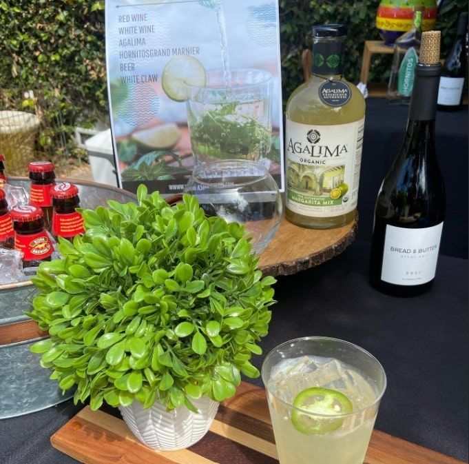 Outdoor drink display with cocktails, liquor bottles, and a small potted green plant