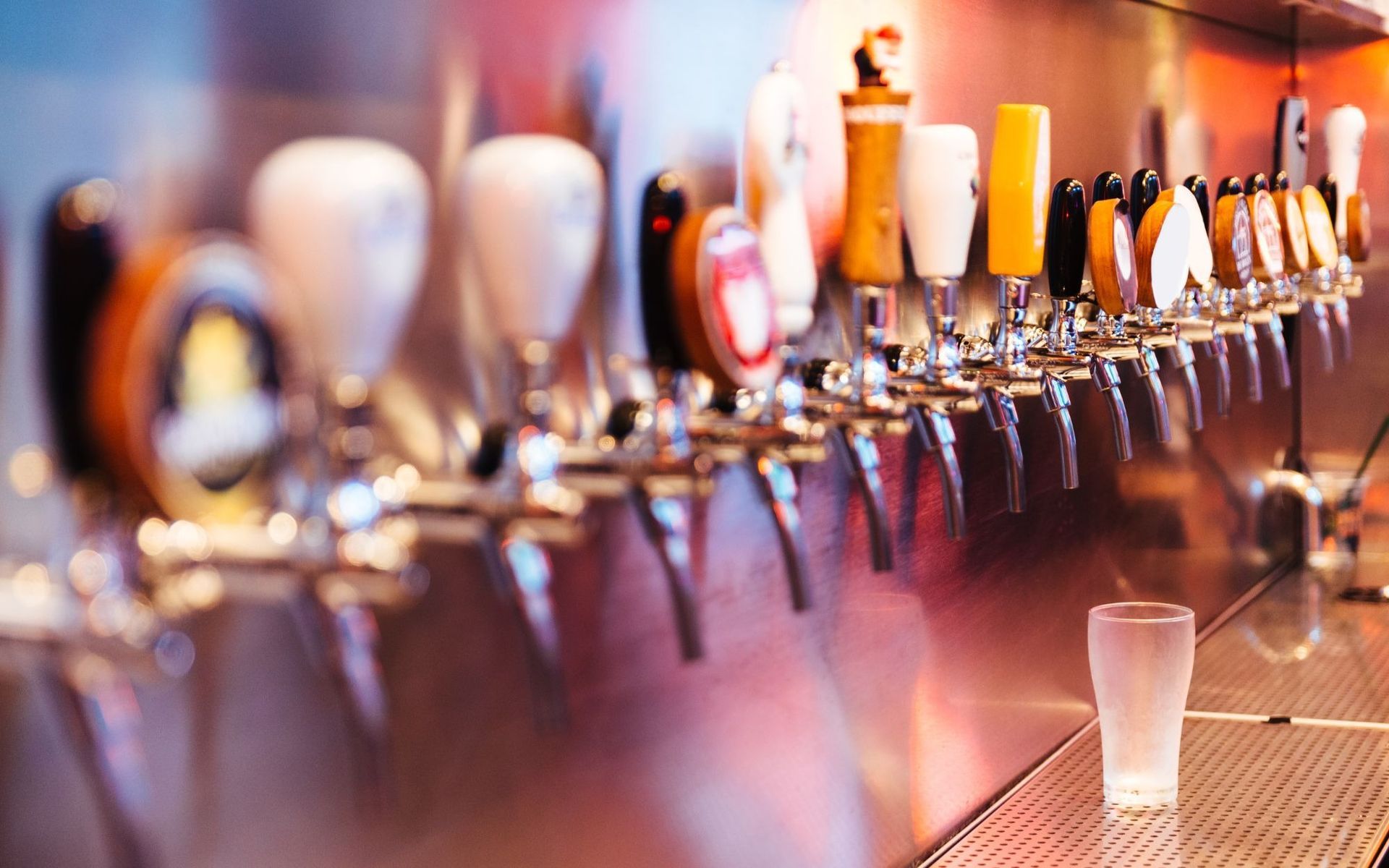 Row of beer taps at a bar with a clear plastic cup on the counter