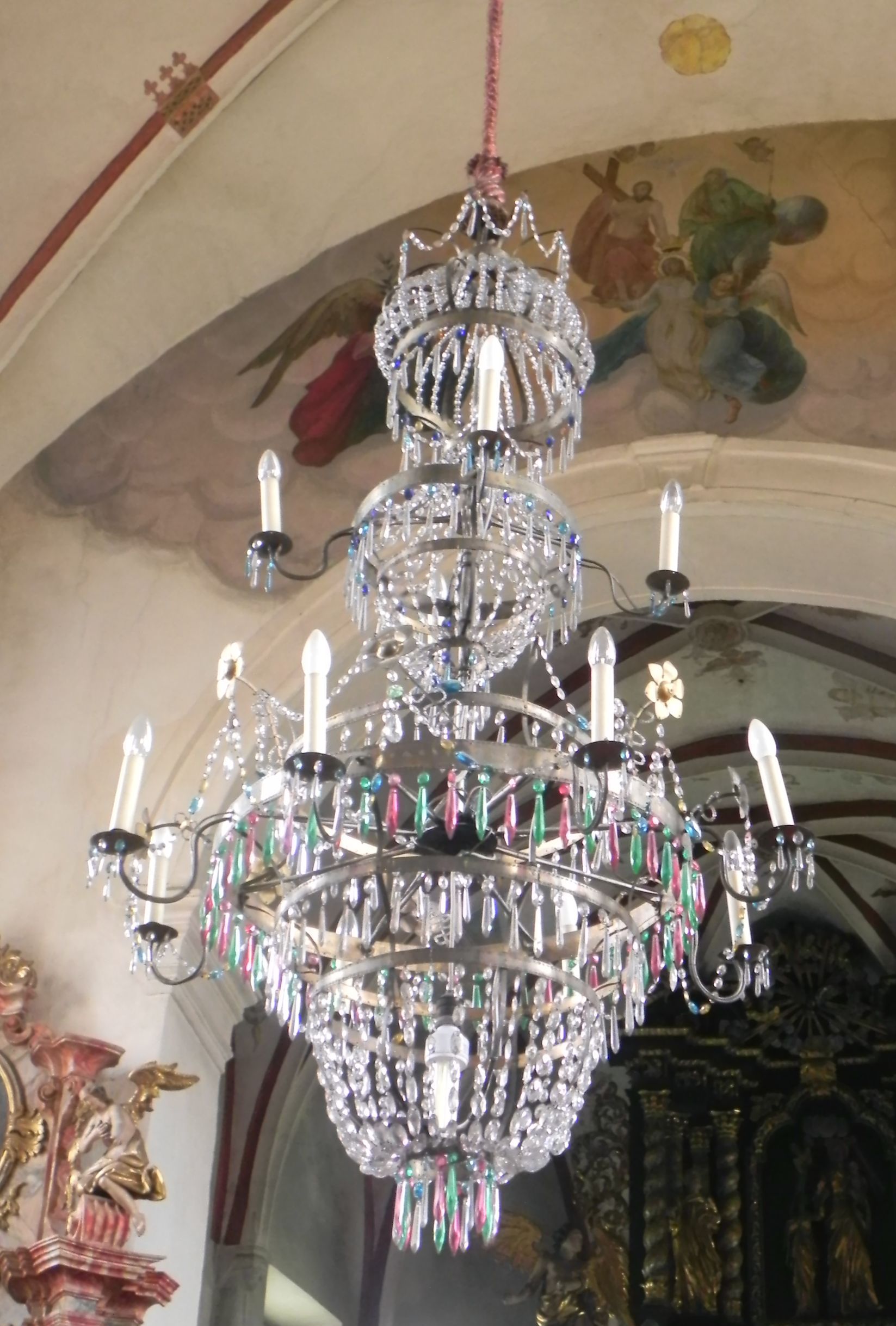 ein großer Kronleuchter hängt über einem weißen Tisch mit der Aufschrift heiliger antonius von padua bitte für uns