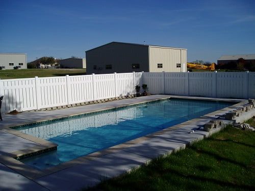 A large swimming pool with a white fence around it
