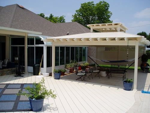 A patio with a pergola and a hammock in front of a house