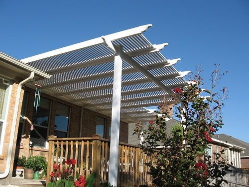A white pergola is sitting on top of a wooden deck.