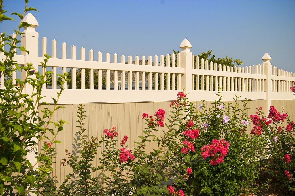 A white picket fence surrounds a garden with pink flowers.