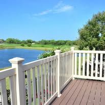 A deck with a white railing overlooking a lake and a golf course.