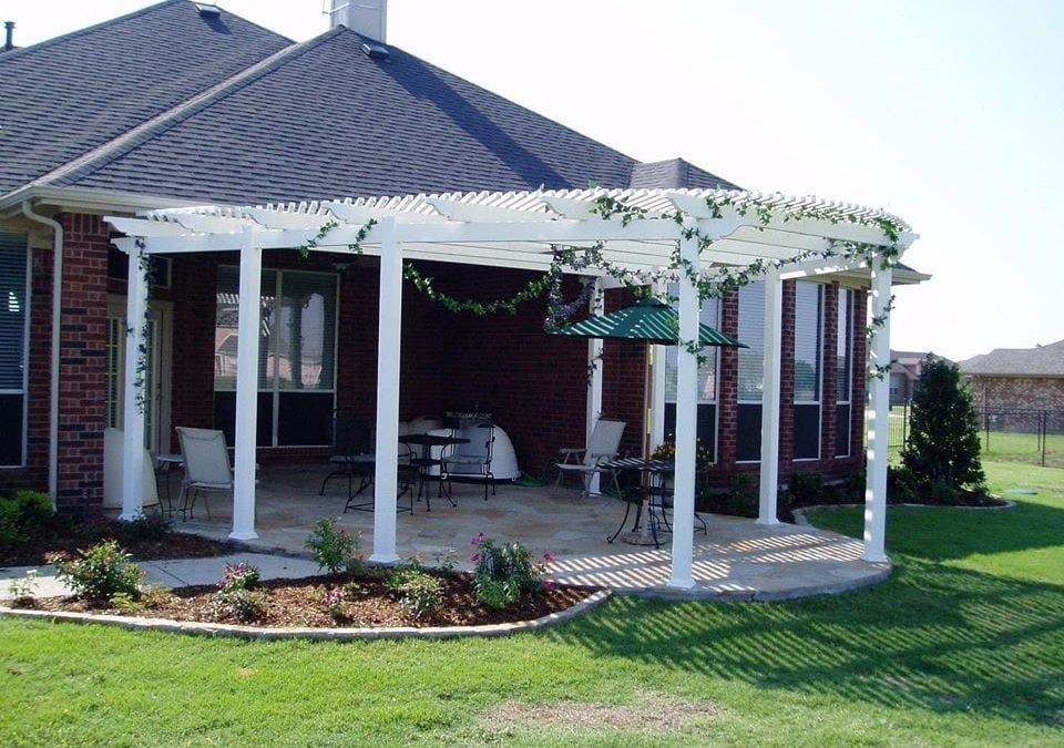 A brick house with a white pergola and a green umbrella