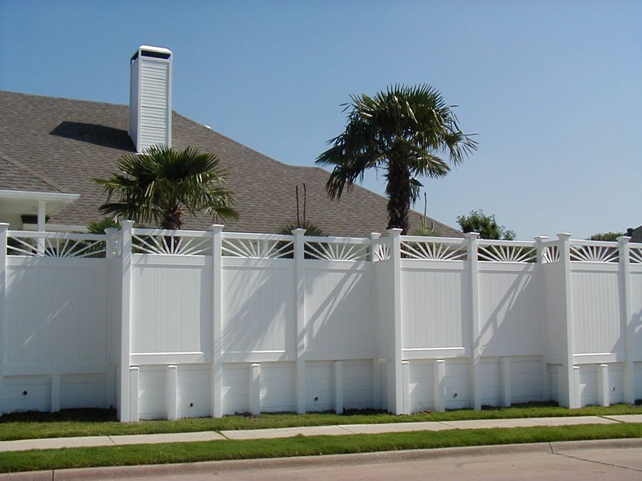 A white fence with palm trees in front of a house