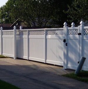 A white vinyl fence with a lattice top and a gate.