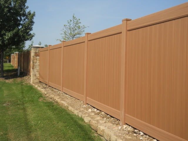 A wooden fence surrounds a lush green yard