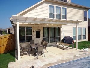 A house with a pergola over a patio next to a pool.