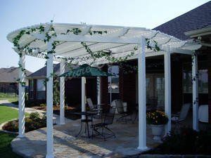 A white pergola is sitting on top of a patio next to a house.