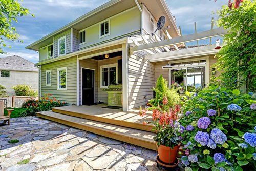 A large house with a patio and flowers in front of it.