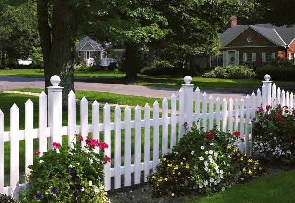 A white picket fence with flowers in front of it