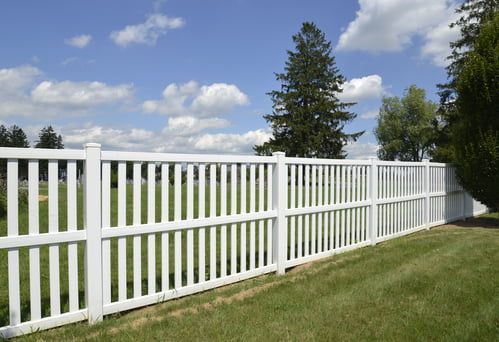 A white fence surrounds a lush green field.