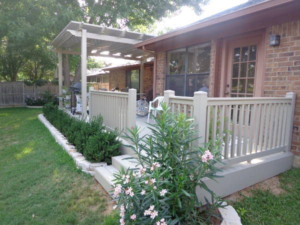 A brick house with a porch and flowers in front of it