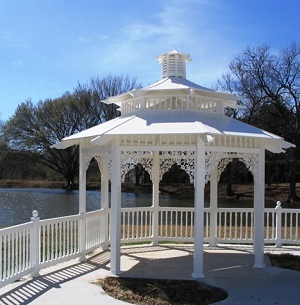 A white gazebo with a white railing overlooking a body of water