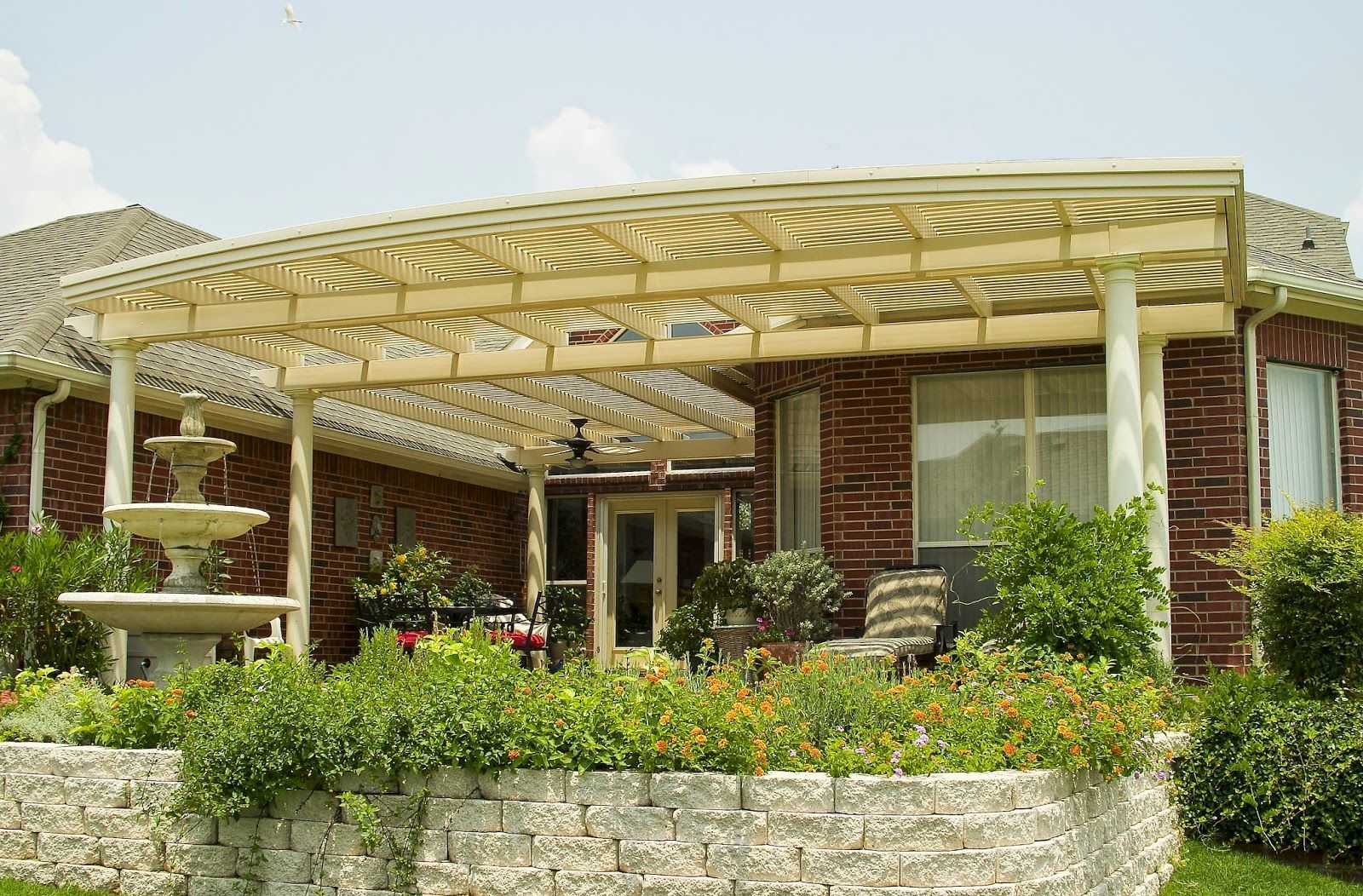 A house with a pergola and a fountain in front of it