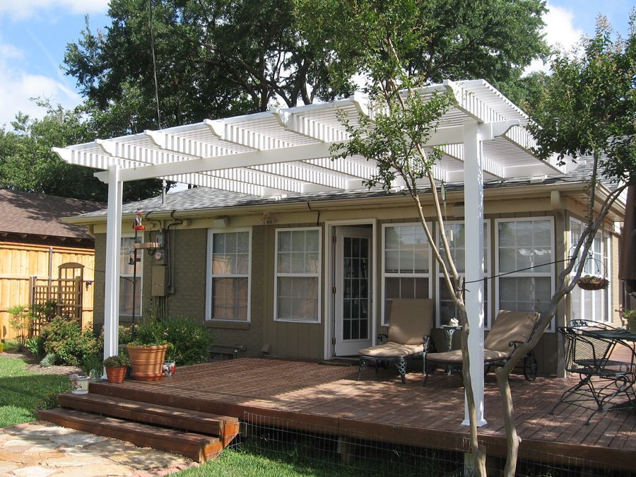 A house with a white pergola and a wooden deck