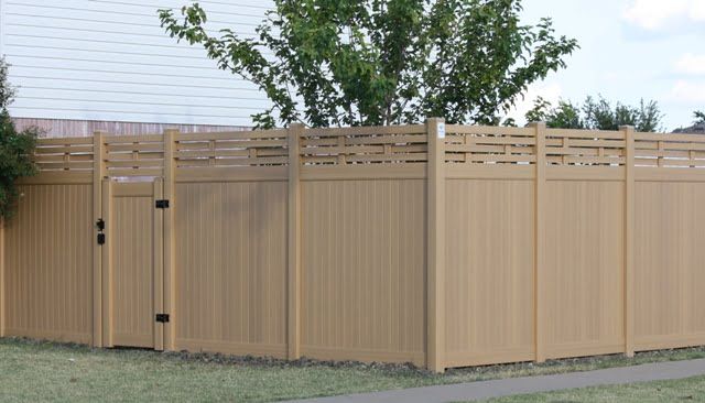 A wooden fence with a gate and a tree in the background