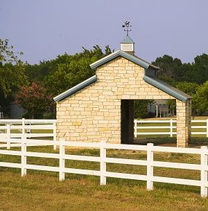 A small brick building with a white fence around it.