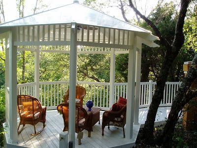 A gazebo with rocking chairs and a table on it