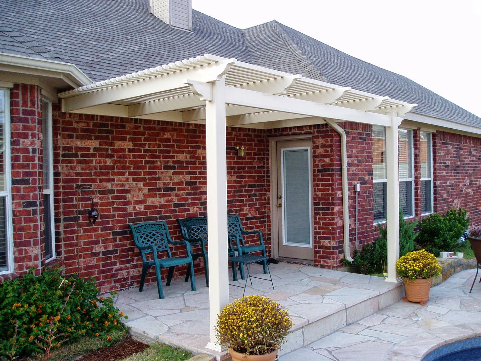 A brick house with a white pergola and chairs