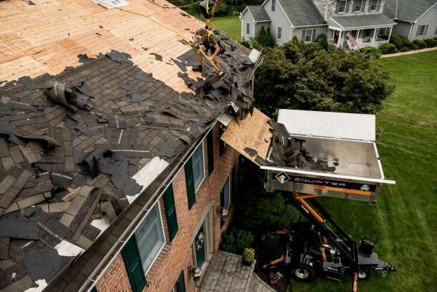 An aerial view of a roof being removed from a house.