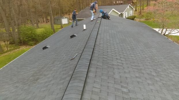 A group of people are working on the roof of a house.