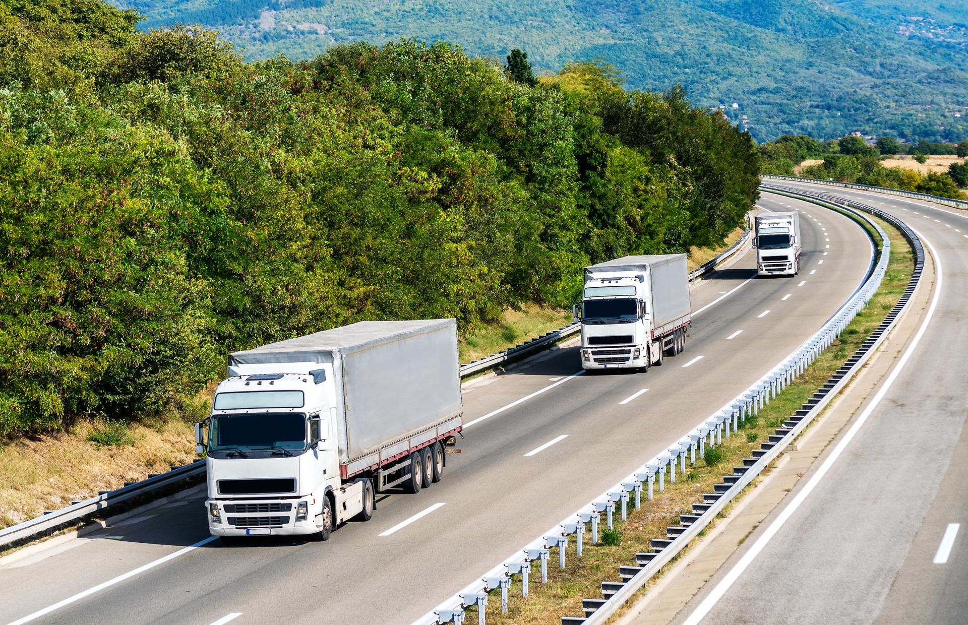 A group of trucks are driving down a highway.