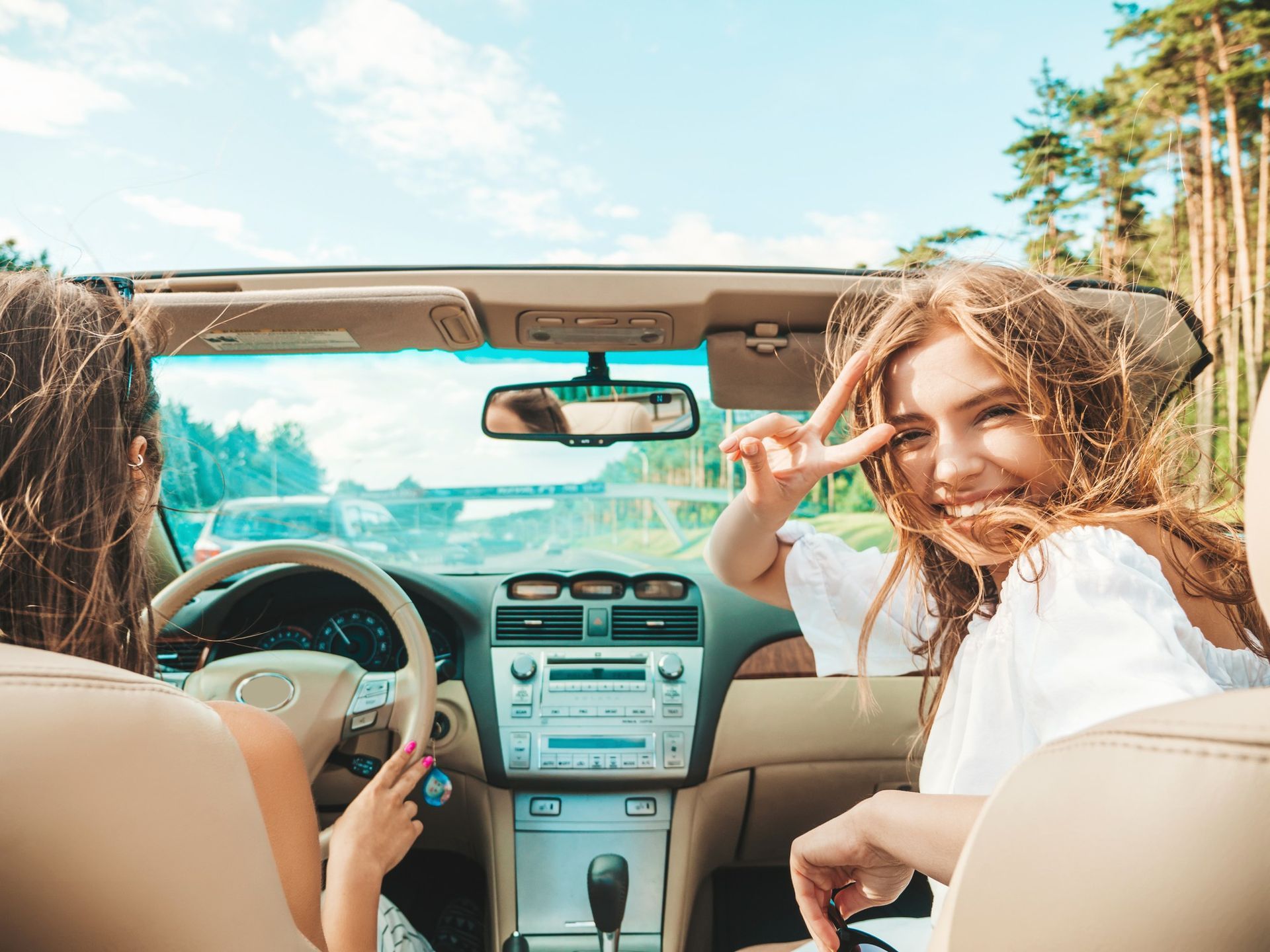 Two young women are sitting in a convertible car.