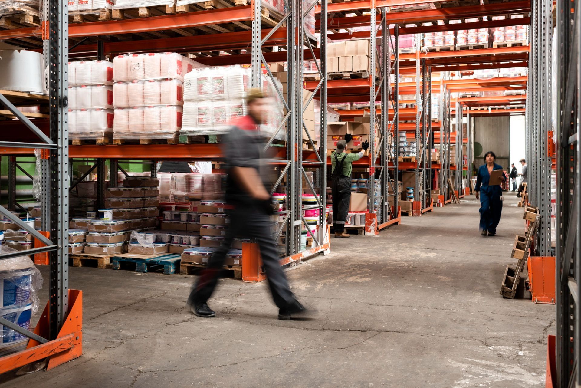 A man is walking through a warehouse filled with shelves and boxes.