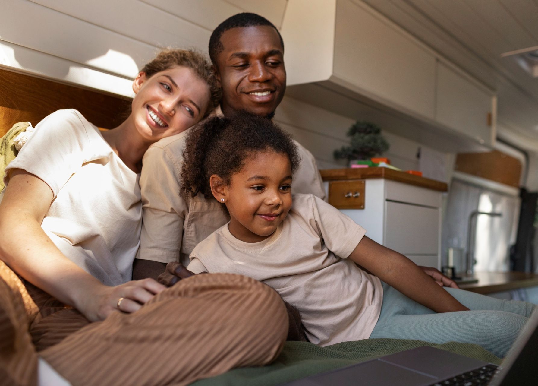A family is sitting on the floor looking at a laptop.