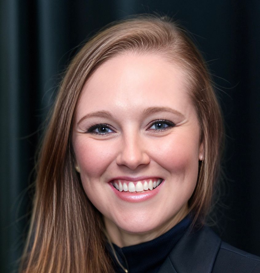 A woman in a black jacket is smiling for the camera.