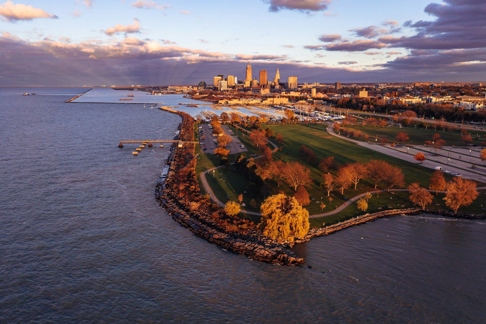 An aerial view of a park next to a body of water with a city in the background.