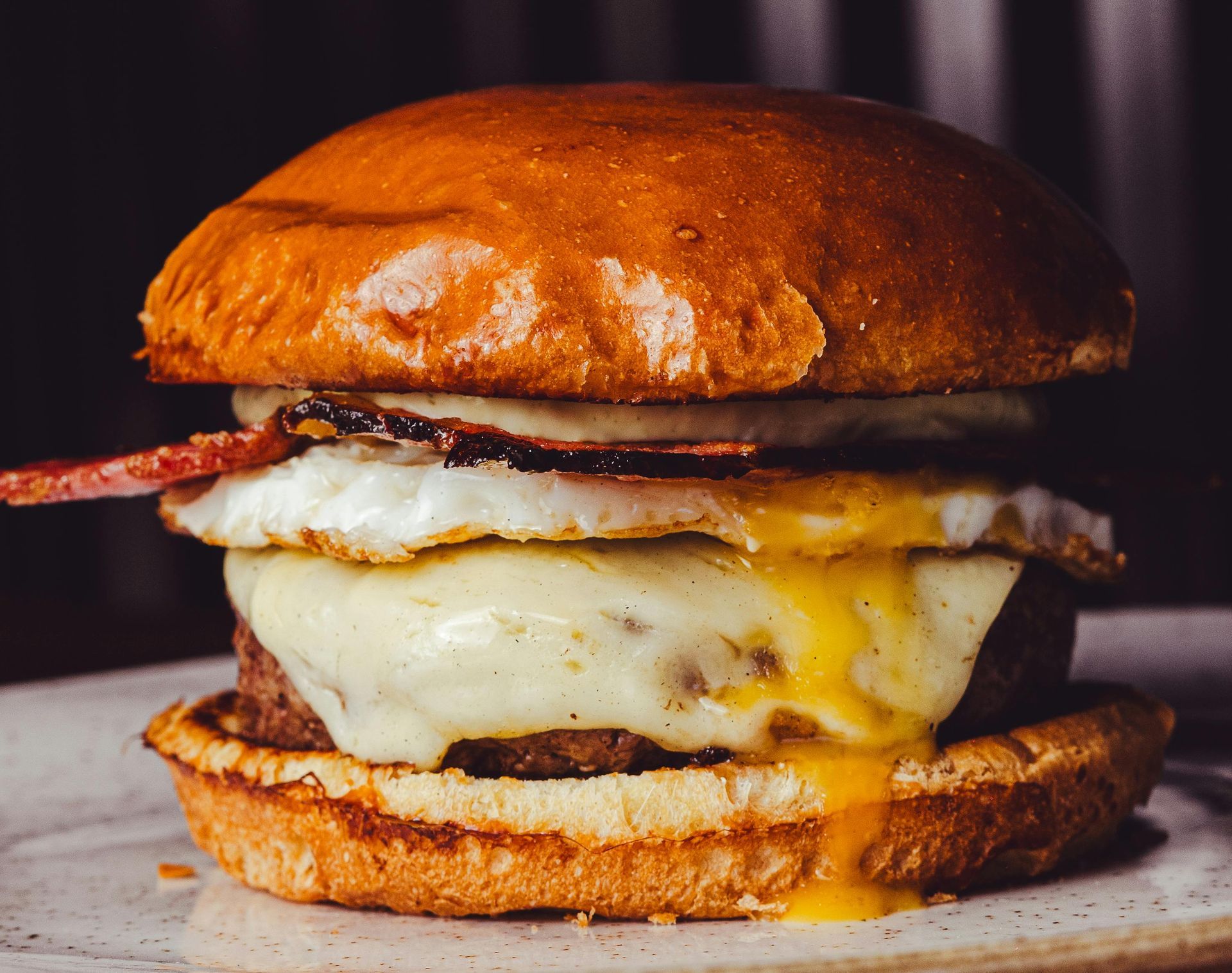 Close-up of a cheeseburger with melted cheese, crispy bacon, and a glossy toasted bun.
