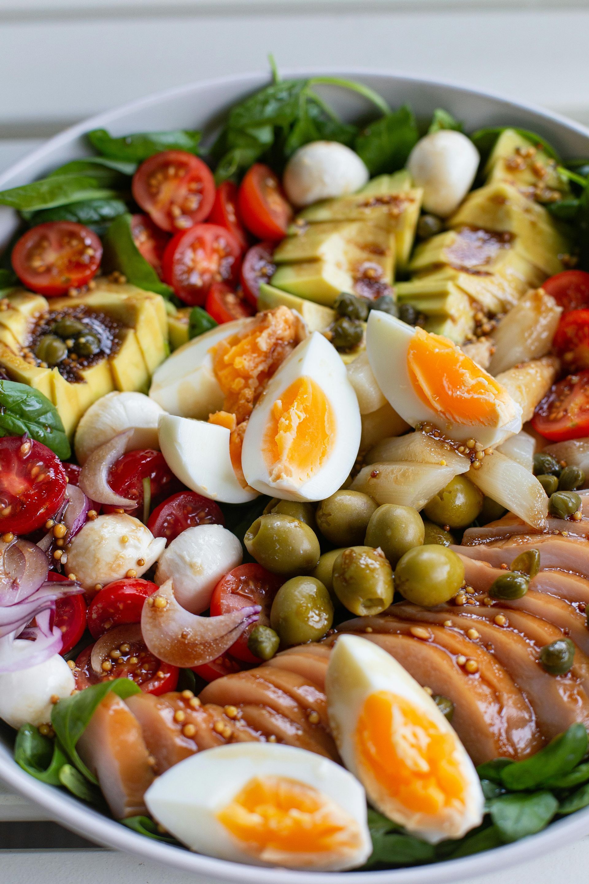 Colorful seafood salad with avocado, cherry tomatoes, eggs, olives, and greens on a plate
