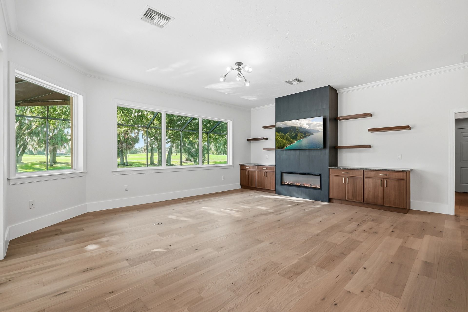 Living room with dark tiled fireplace accent wall, floating wood shelves, and wood-look flooring