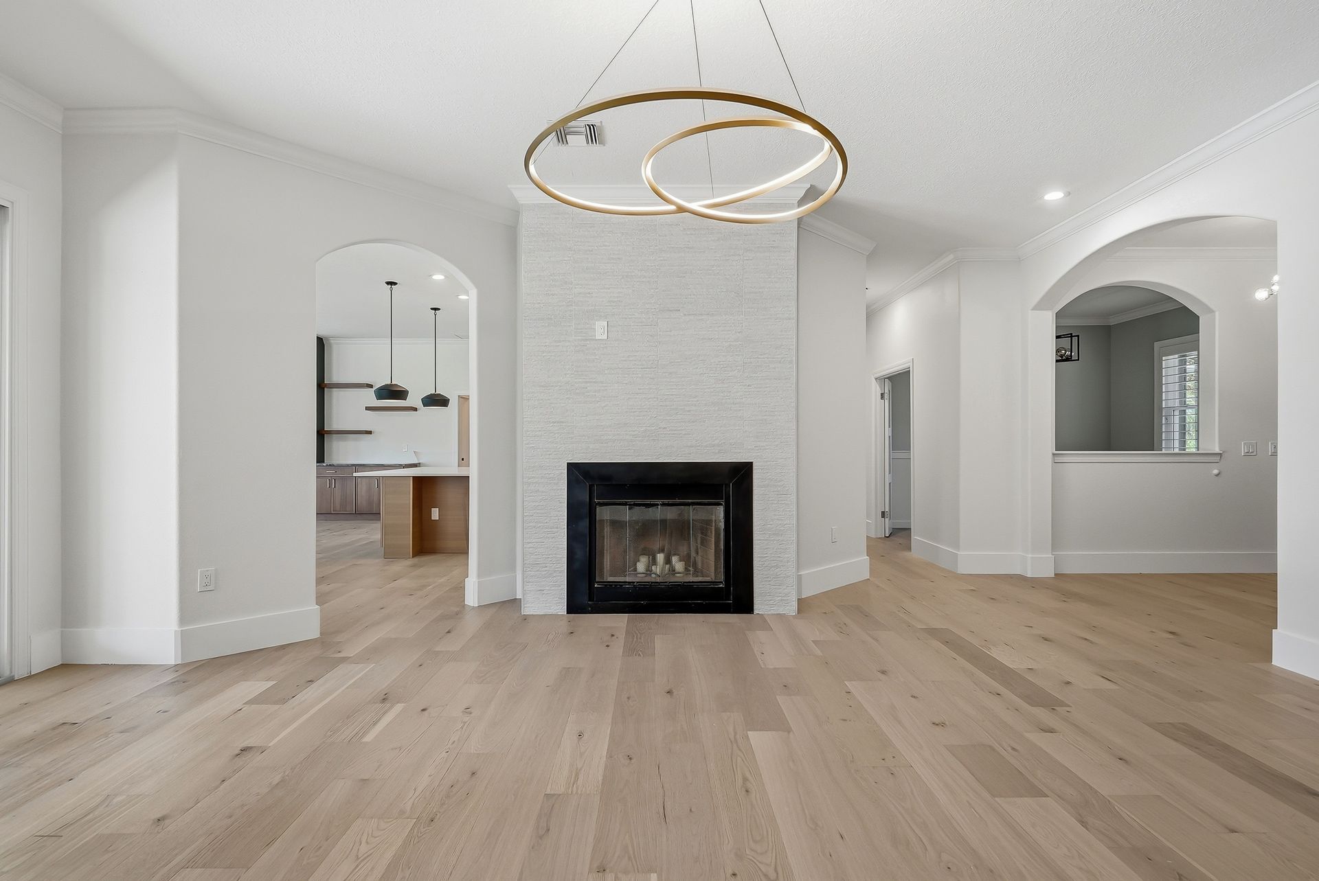 Living room with floor-to-ceiling stone-look tile fireplace accent wall and modern ring pendant lighting