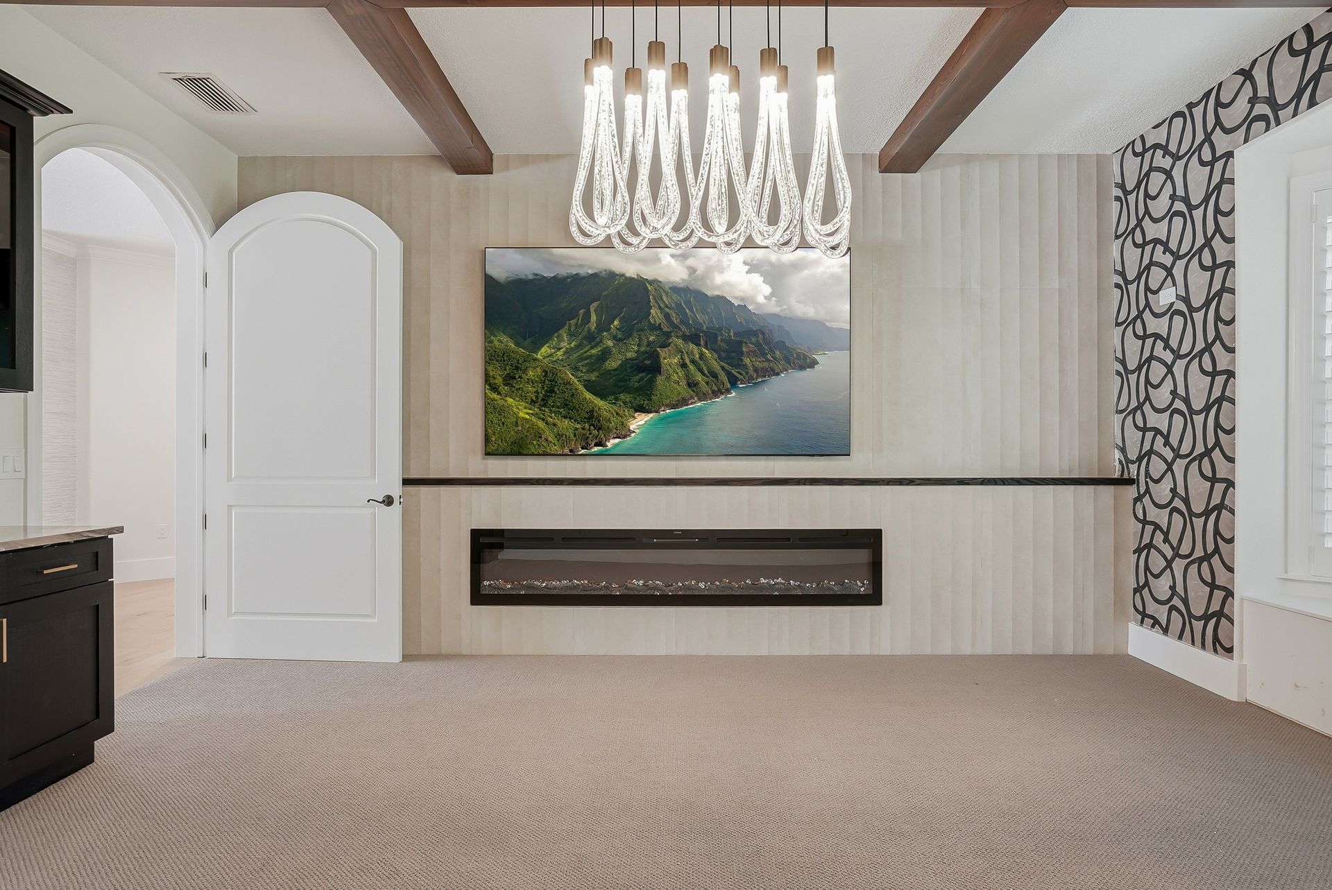 Living room accent wall with vertical wood slat paneling, linear electric fireplace, and crystal pendant chandelier