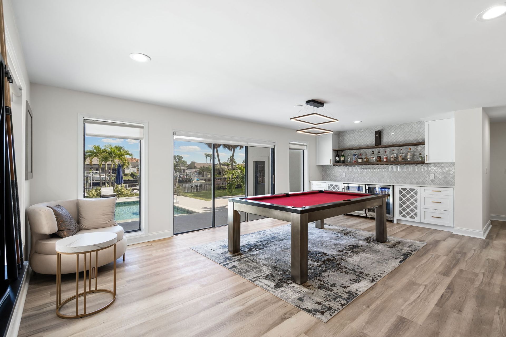 Bright game room with pool table, wet bar, large windows, and sliding doors to a backyard view