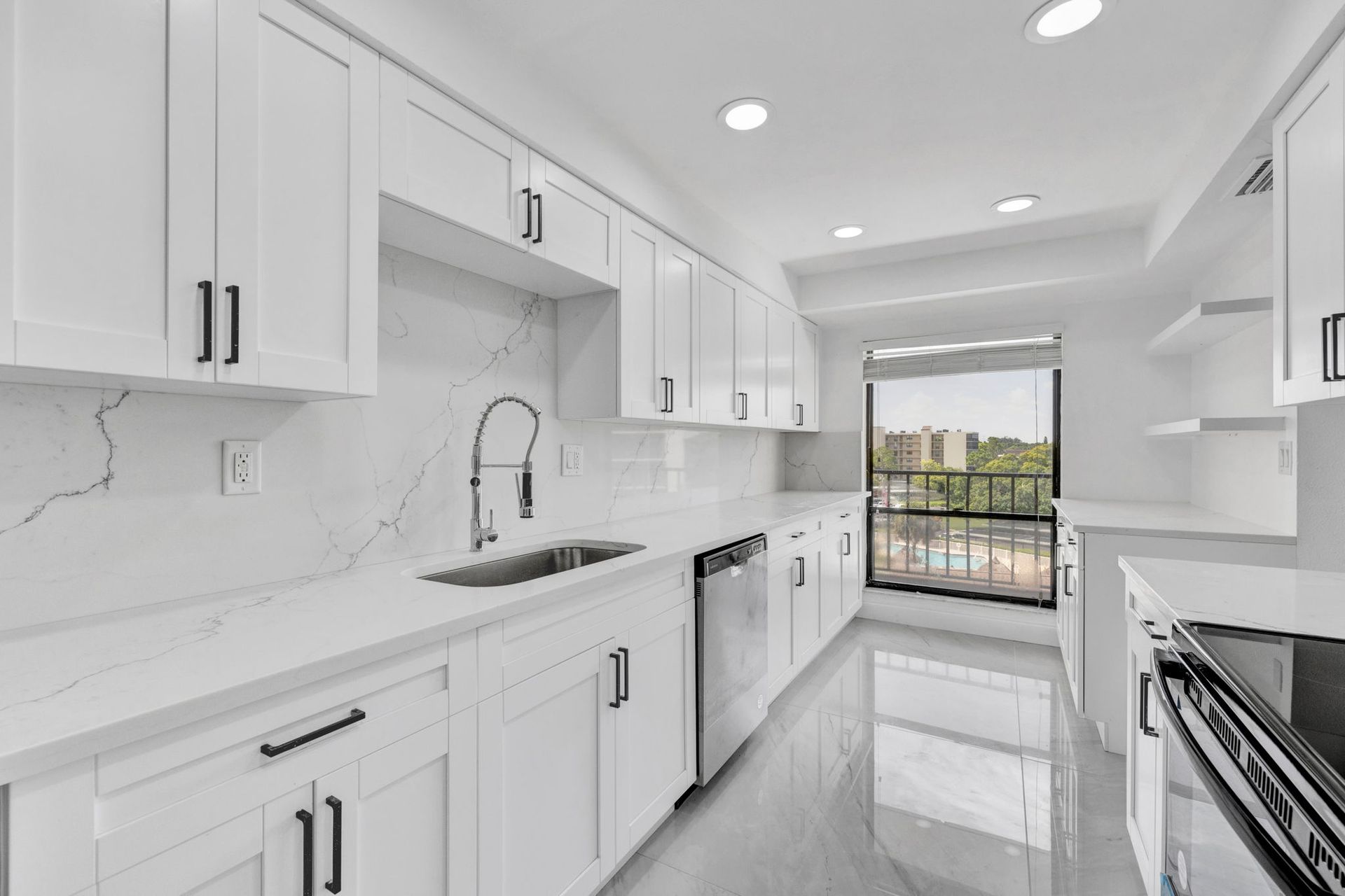 White shaker kitchen with marble-look quartz countertops and backsplash, stainless steel appliances, and a view overlooking the pool