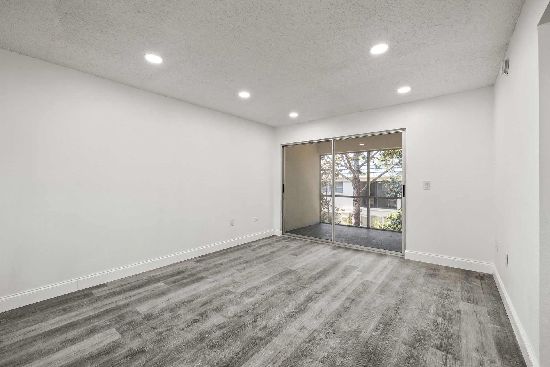 Empty white room with gray carpet and sliding glass door to a patio