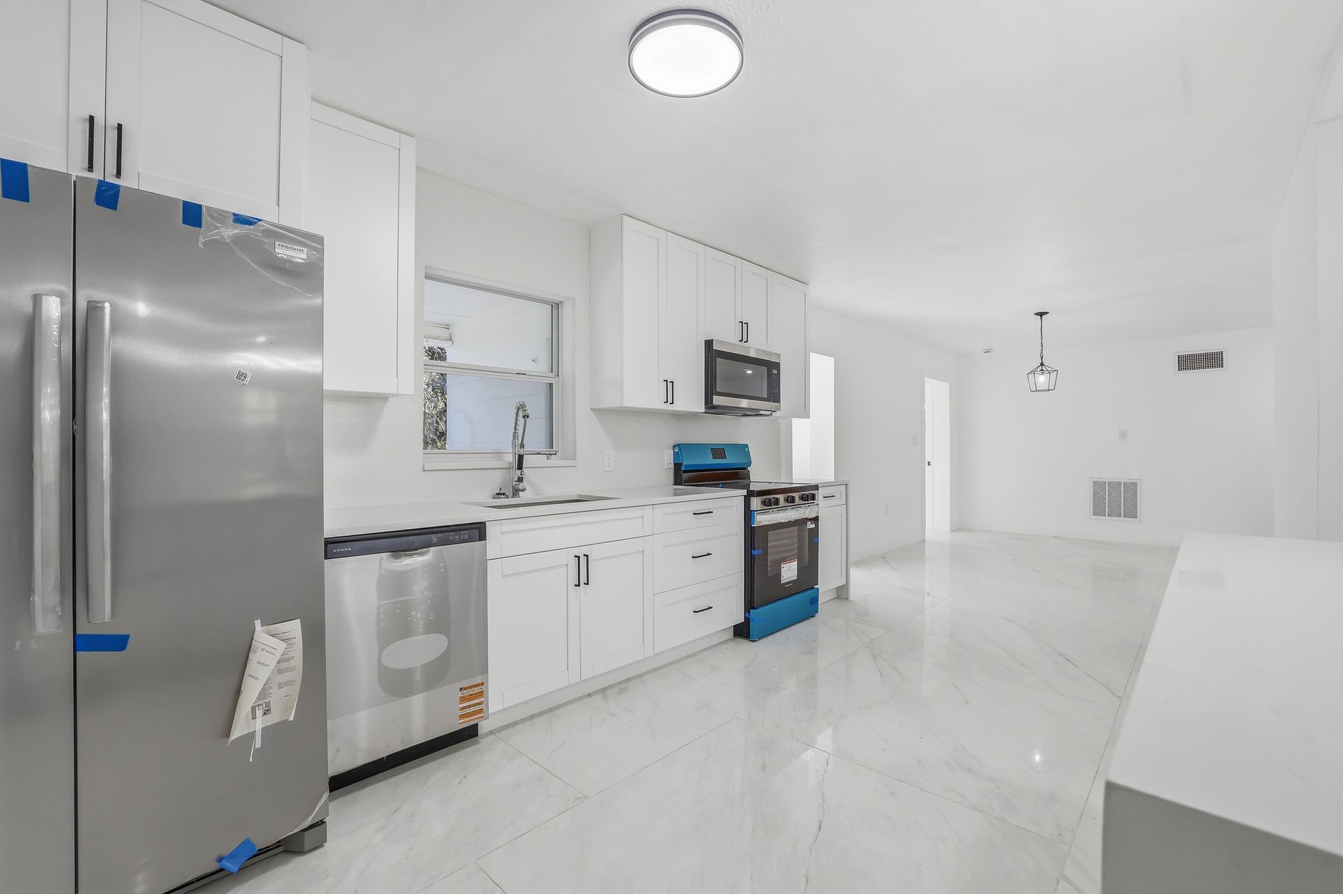 Bright white modern kitchen with stainless appliances and glossy tile floor