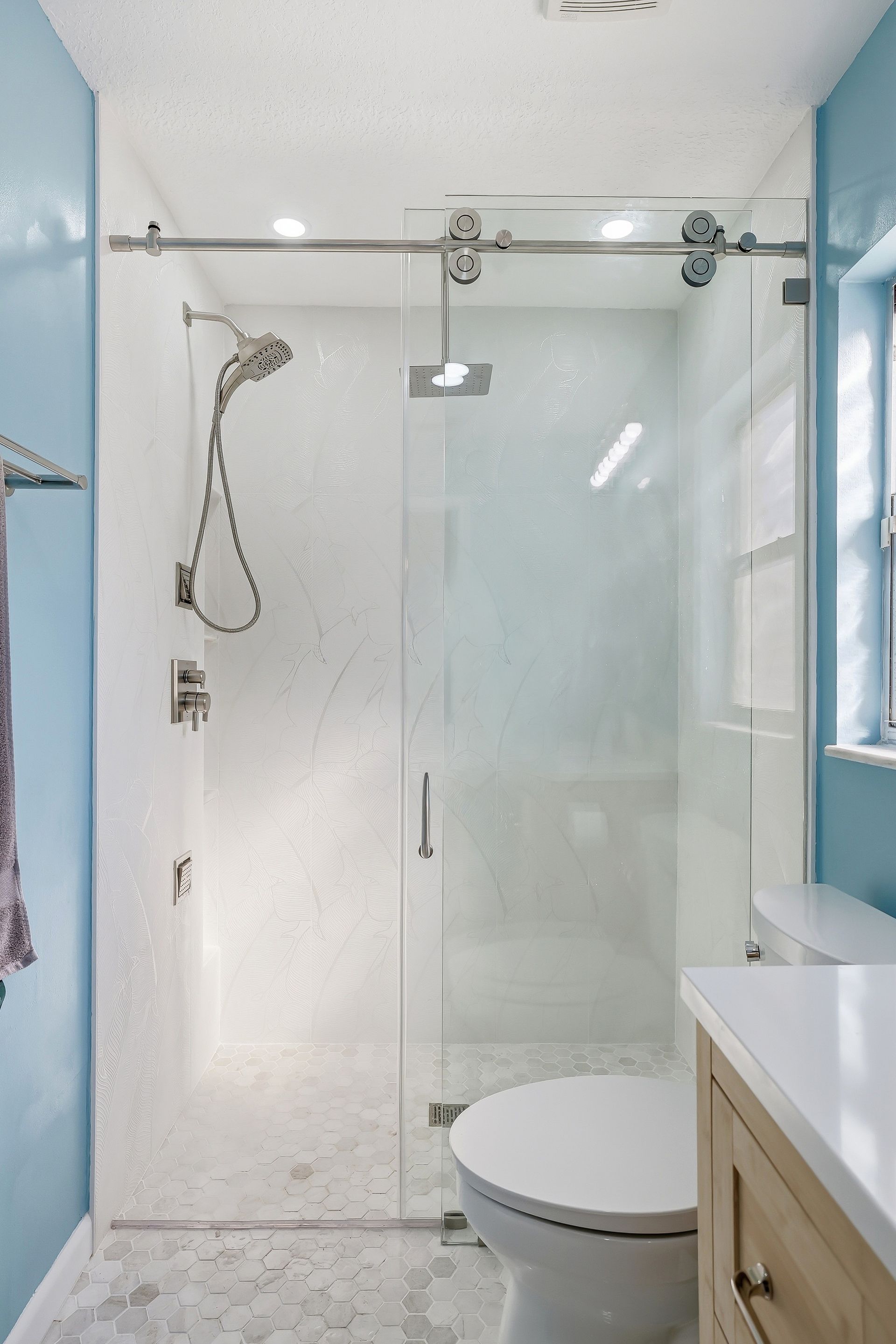 Modern bathroom with glass shower, rainfall showerhead, and white vanity sink