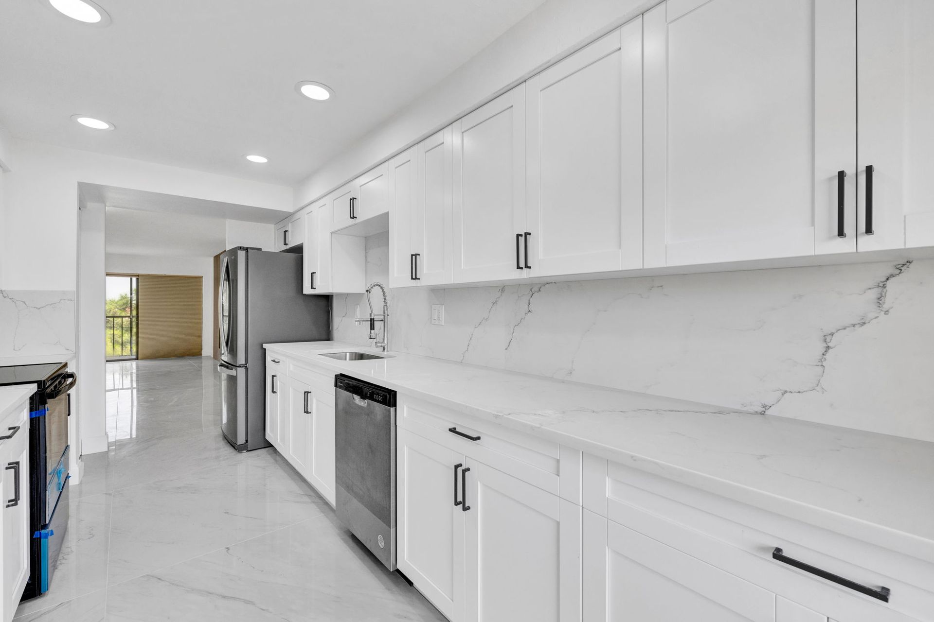 Bright modern kitchen with white cabinets, marble countertops, and stainless steel appliances
