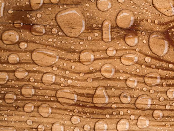 Close-up of brown wood grain with scattered water droplets