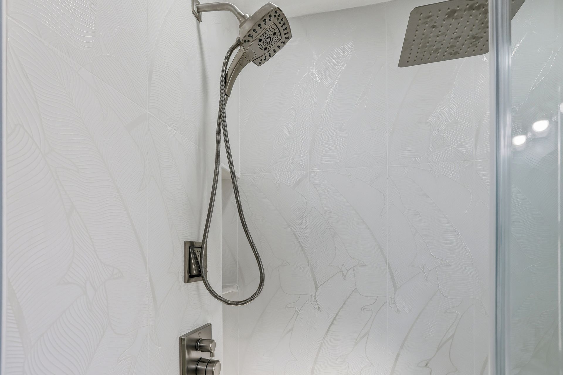 Showerhead and hose in a white tiled shower stall