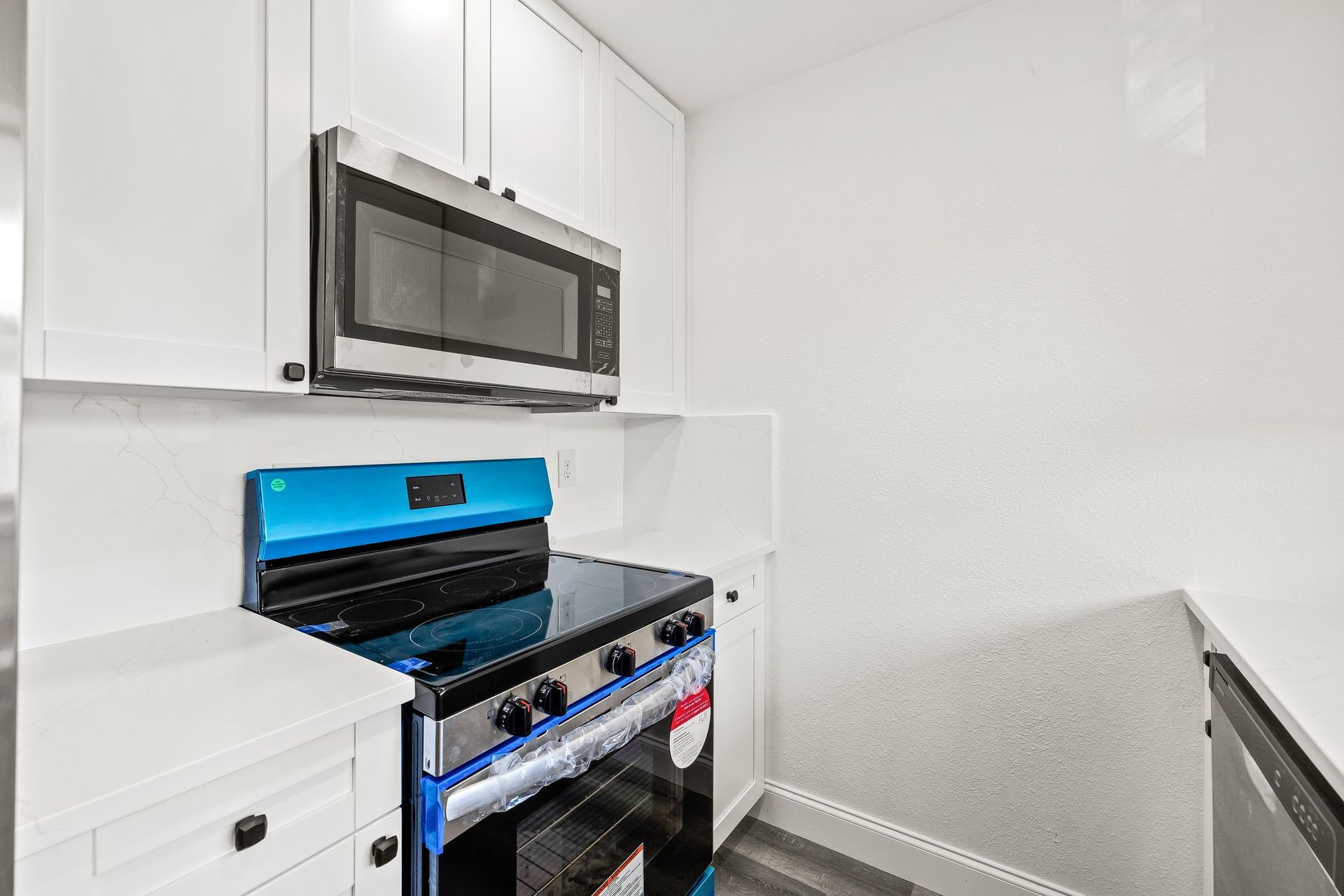 Modern kitchen with stainless steel stove and over-the-range microwave against white cabinets