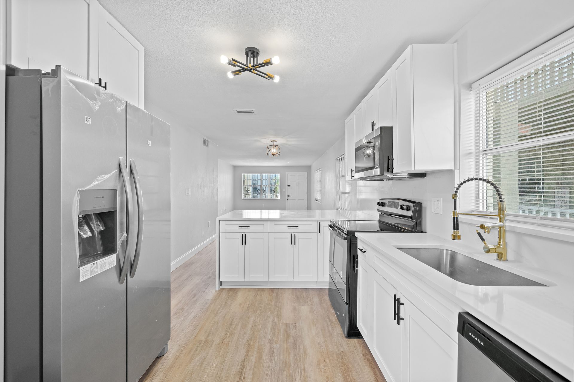 Bright modern kitchen with stainless fridge, white cabinets, and light wood floors